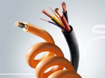 Coiled orange and black EV charging cables with exposed multi-core copper wires for electric vehicle assemblies